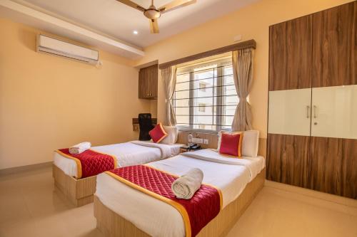 een slaapkamer met 2 bedden en een raam bij MK Residency in Coimbatore