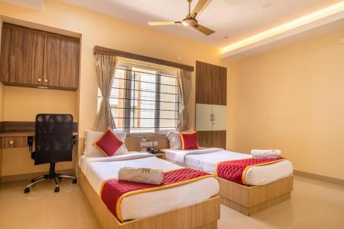ein Hotelzimmer mit zwei Betten und einem Fenster in der Unterkunft MK Residency in Coimbatore