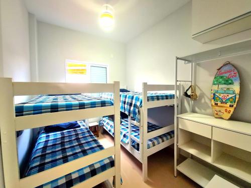 a room with three bunk beds and a surfboard at Apartamento com piscina em UBATUBA in Ubatuba