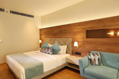 a bedroom with a bed and a blue chair at Indus Biznotel in New Delhi