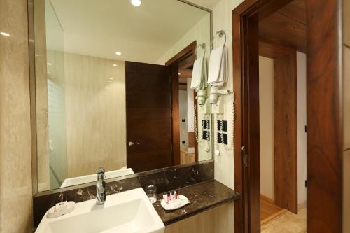 a bathroom with a sink and a large mirror at Indus Biznotel in New Delhi