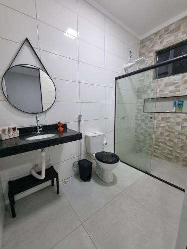 a bathroom with a toilet and a sink and a mirror at Chácara Lótus in Trindade