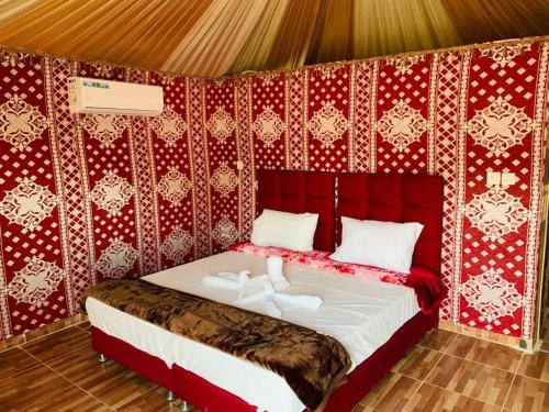 a bed in a room with a red wall at sand magic camp in Wadi Rum