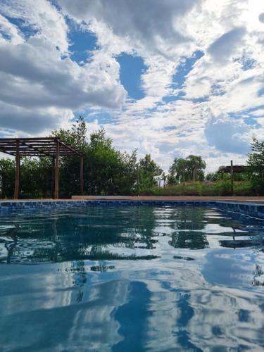 a swimming pool with a cloudy sky in the background at Chácara Lótus in Trindade