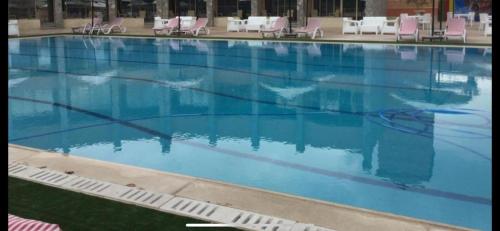 uma grande piscina com água azul e cadeiras cor-de-rosa em Nile jewel hotel beni suef em Beni Suef