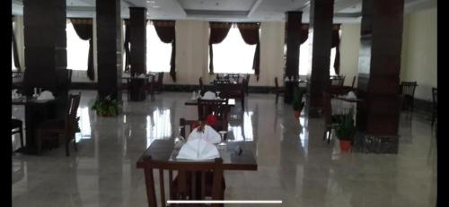 un comedor con mesas, sillas y ventanas en Nile jewel hotel beni suef, en Beni Suef