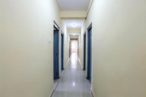 a hallway of a building with blue doors and white walls at Simsan Inn in Chennai