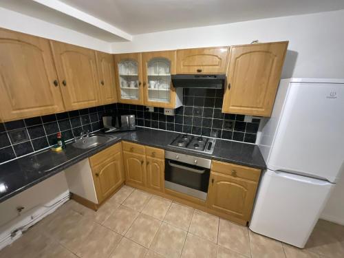 - une cuisine avec des placards en bois et un réfrigérateur blanc dans l'établissement Spacious 2 bed Dulwich flat green views, à Londres