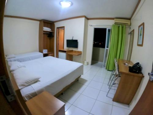 a bedroom with a bed and a desk and a television at Suíte Grand Hotel Dolphin in Caldas Novas