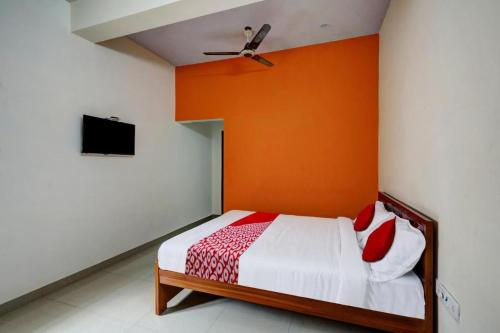 a bedroom with a bed with an orange wall at Simsan Inn in Chennai