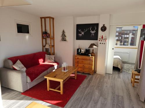 un salon avec un canapé rouge et une table dans l'établissement La Foux d'Allos - Appartement T2 cosy et lumineux en cœur de station, à La Foux