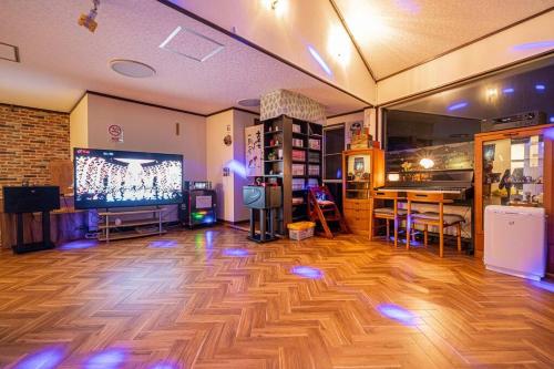a large room with a wooden floor and a large screen tv at 団体歓迎ジョイサウンドカラオケ付き北軽井沢超大型貸別荘7寝室5浴室20人泊まれる in Karuizawa