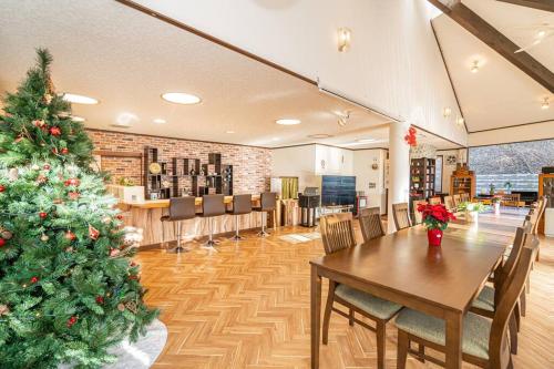 a christmas tree in a room with a table and chairs at 団体歓迎ジョイサウンドカラオケ付き北軽井沢超大型貸別荘7寝室5浴室20人泊まれる in Karuizawa