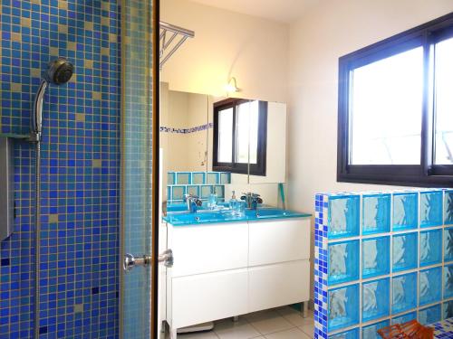baño con lavabo y pared de azulejos azules en Magnifique villa 220m2- Quartier résidentiel Le Carreyrat - 6 à 8 pers - 3 chambres doubles - Grand jardin et terrasses, en Montauban