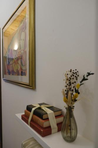 a group of books sitting on a shelf with a vase at Dimora Amina in Loreto Aprutino