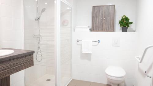 a white bathroom with a toilet and a shower at Zenao Appart'Hotel in Yzeure