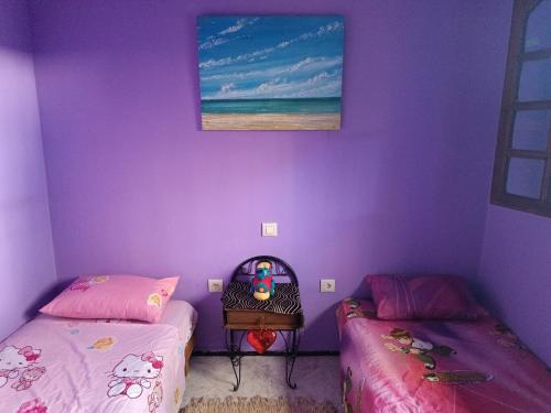 two beds in a room with purple walls at Dar Dyafa in Salé