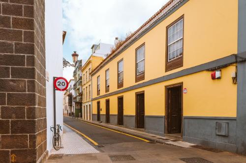 una calle con edificios amarillos y una señal de no estacionamiento en Marhaba La Laguna, alojamiento en centro histórico de San Cristóbal de La Laguna, en La Laguna