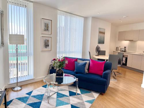 a living room with a blue couch and a table at Urban Gateway Spacious Apartment with free parking in Bracknell