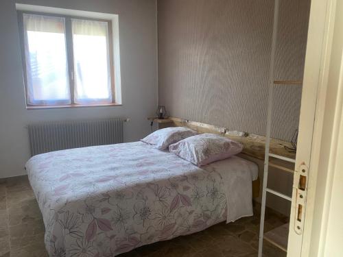 um pequeno quarto com uma cama e uma janela em Pivoine em Bellegarde-sur-Valserine