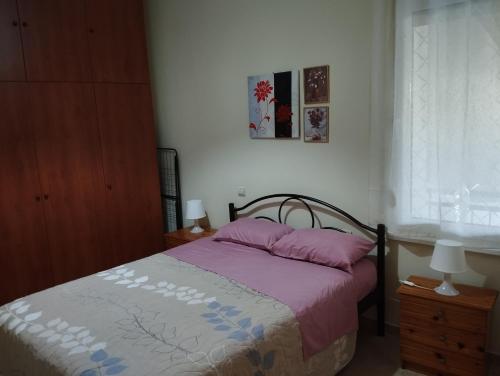 a bedroom with a bed with pink pillows and a window at THREE BROTHERS in Dhidhimótikhon