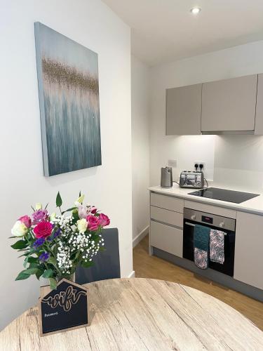 a kitchen with a table with a vase of flowers at Urban Gateway Spacious Apartment with free parking in Bracknell
