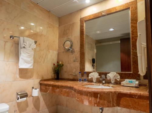 ein Bad mit einem Waschbecken und einem Spiegel in der Unterkunft Emaar Royal Hotel in Medina