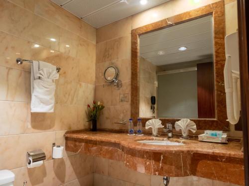 a bathroom with a sink and a mirror at Emaar Royal Hotel in Medina