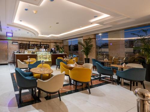 a restaurant with tables and chairs and a bar at Emaar Royal Hotel in Al Madinah