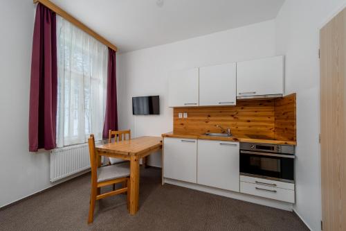a kitchen with white cabinets and a wooden table at Pension Janský Potok I. in Janske Lazne
