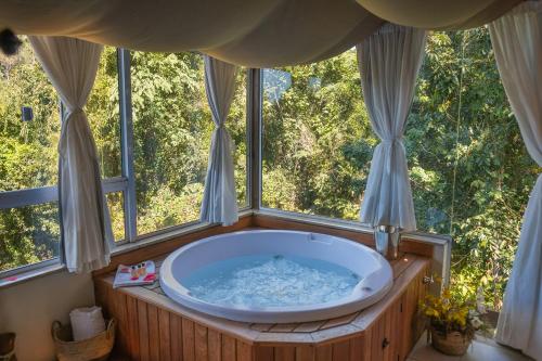 bañera grande en una habitación con ventanas en Bombinhas Guest House, en Bombinhas