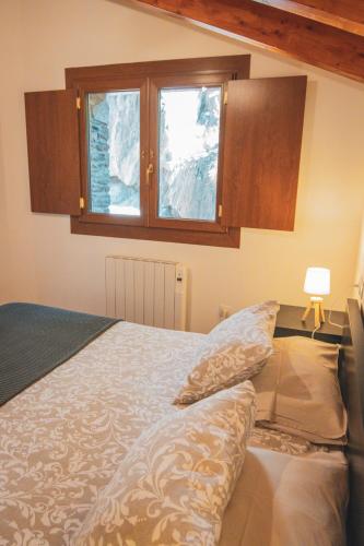 a bedroom with a bed with pillows and a window at Casa amb molt encant i tranquilitat. in Ansalonga