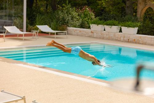 a person is diving into a swimming pool at Villa Rosato in Selva di Fasano