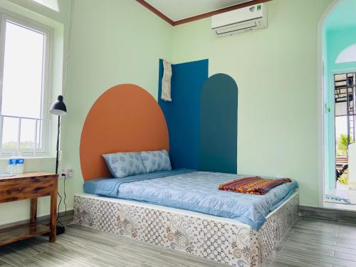 - une chambre dotée d'un lit avec un mur orange et bleu dans l'établissement Gió Homestay and Coffee, à Ấp Khánh Phước (1)