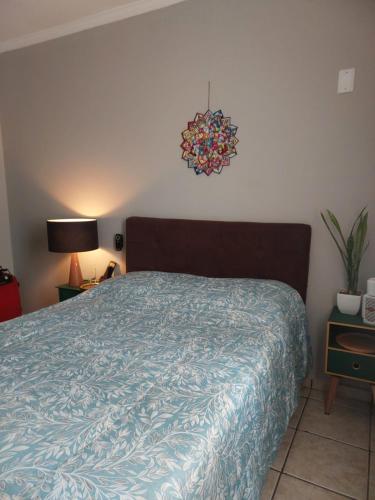 Schlafzimmer mit einem Bett mit blauer Decke in der Unterkunft Quarto com Cama de Casal in Sorocaba