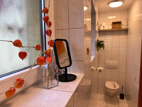 a bathroom with a mirror and a vase with flowers at Gasthaus Wini in Wanzleben