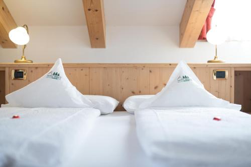 two white beds in a room with two lamps at Hotel Zirmes in Moena