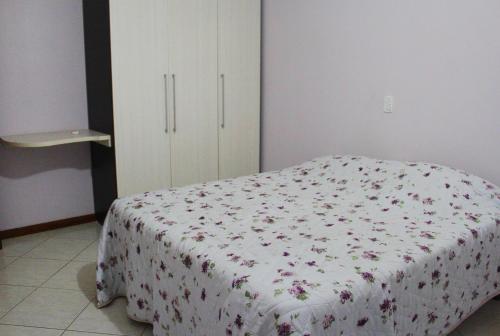 - une chambre dotée d'un lit avec un couvre-lit floral dans l'établissement Cantinho Aconchegante Morada do Sol, à Piratuba