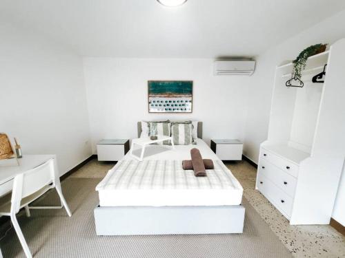 Habitación blanca con cama blanca y escritorio. en Flamboyan - Condado Apt Walking to Beach W/ PRK en San Juan