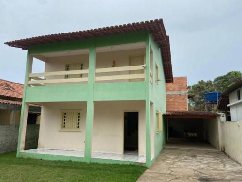 un edificio verde y blanco con patio en Casa de praia para temporada espaço inteiro Putiri ES, en Santa Cruz