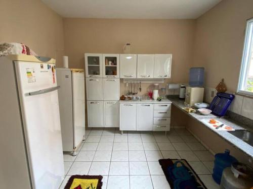 una cocina con electrodomésticos blancos y armarios blancos en Casa de praia para temporada espaço inteiro Putiri ES, en Santa Cruz