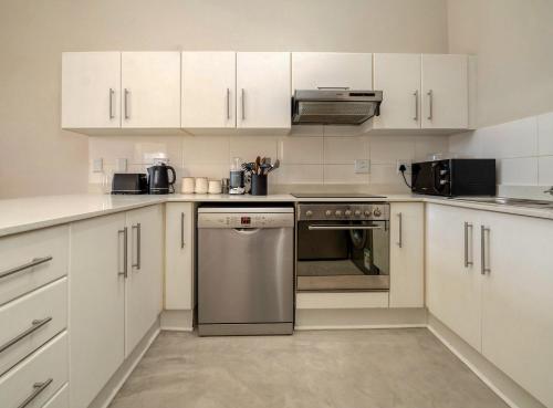 - une cuisine avec des placards blancs et un lave-vaisselle en acier inoxydable dans l'établissement Beachfront apartment, au Cap