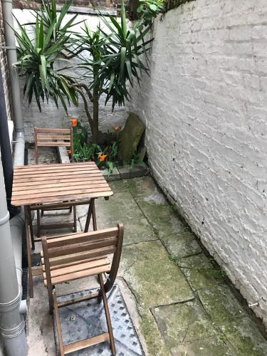 ロンドンにあるLondon Homeのレンガの壁の横に並ぶ木製テーブルと椅子2脚