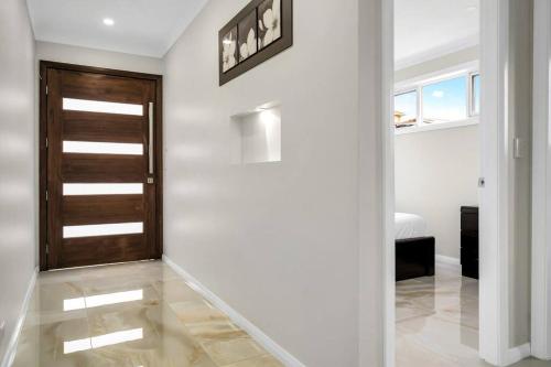 a hallway with a wooden door and white walls at Large Family Home with plenty of amenities in Campbelltown