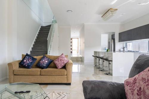 a living room with a couch and a staircase at Large Family Home with plenty of amenities in Campbelltown