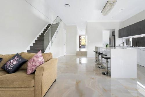 a living room with a couch and a kitchen at Large Family Home with plenty of amenities in Campbelltown