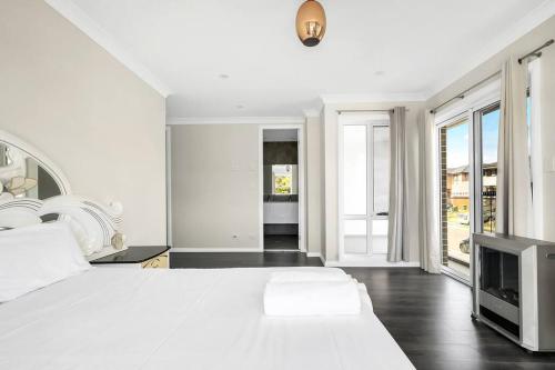 a white bedroom with a large bed and a tv at Large Family Home with plenty of amenities in Campbelltown