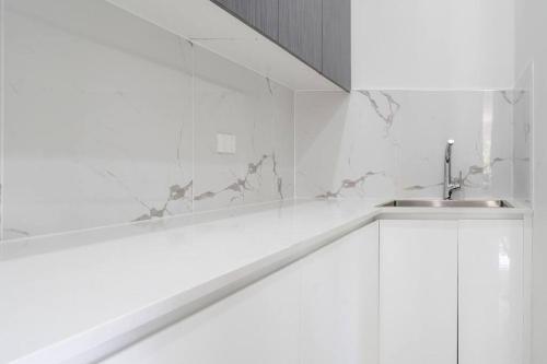 a white bathroom with a sink and a mirror at Large Family Home with plenty of amenities in Campbelltown