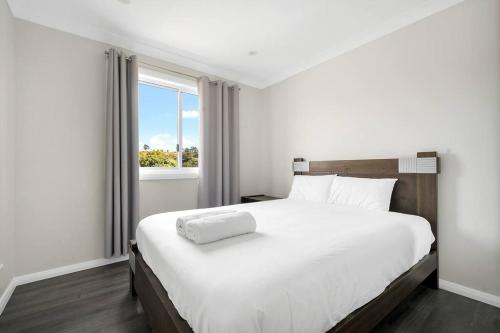a bedroom with a large white bed with a window at Large Family Home with plenty of amenities in Campbelltown