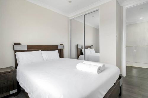 a bedroom with a large white bed and a mirror at Large Family Home with plenty of amenities in Campbelltown